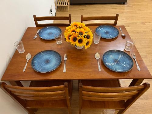 a wooden table with blue plates and a sunflower on it at Infistay Homestay - Sunway Geo Avenue, Sunway Pyramid, Sunway Lagoon, Sunway University, Sunway Medical Centre in Subang Jaya