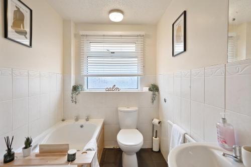 a bathroom with a tub and a toilet and a sink at Stylish Abode with Games Room - Sleeps 15 in Brislington