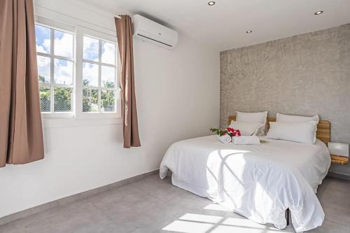 1 dormitorio con cama blanca y ventana en villa de prestige Anse ka'nel en Le Moule