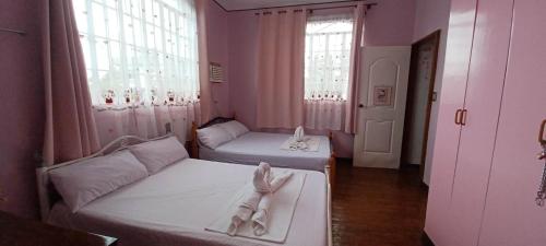 a small room with two beds and two windows at Donsol Aguluz Homestay in Donsol