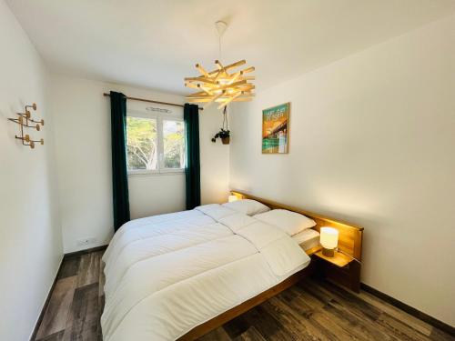 - une chambre avec un grand lit blanc et un lustre dans l'établissement Maison forestière, mer & lumière, à Saint-Jean-de-Monts