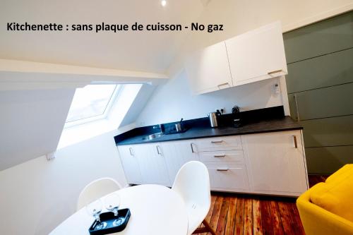 a kitchen with white cabinets and a white table at Les Gîtes Du Palais in Dinant