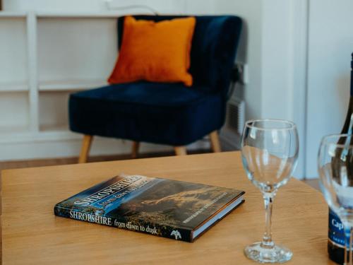 ein Buch auf einem Tisch neben einem Glas in der Unterkunft The Coach House Barn in Shrewsbury