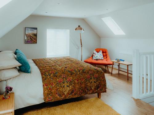 ein Schlafzimmer mit einem Bett und einem orangefarbenen Stuhl in der Unterkunft The Coach House Barn in Shrewsbury