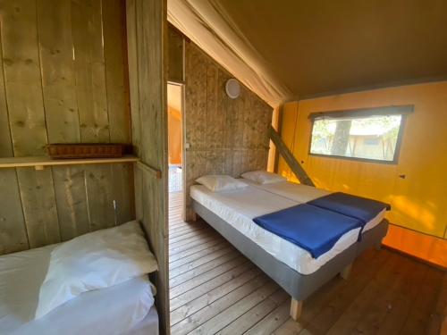 a bedroom with two beds in a wooden cabin at Camping la Kahute - Tente lodge au coeur de la forêt in Carcans