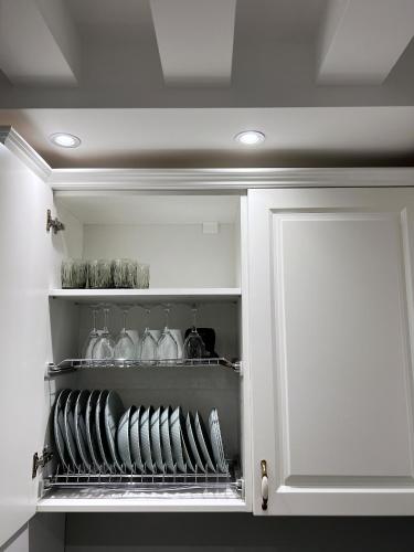 a white cabinet with glasses and plates in it at XIO Apartments in Bar