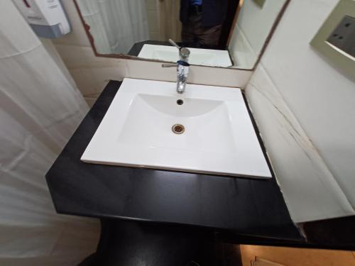 a white sink in a bathroom with a mirror at Broadway Inn in Jaipur