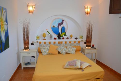 1 dormitorio con 1 cama amarilla grande y 2 mesitas de noche en Villetta Lavanda en Lipari