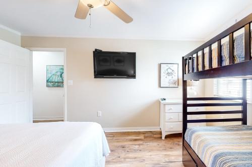 a bedroom with a bunk bed and a flat screen tv at A Wave From It All - Unit B in Gulf Shores