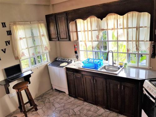 uma cozinha com um lavatório, um fogão e janelas em St. George's Holiday Studio Vacation of a lifetime em Fontenoy