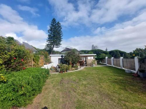 a backyard with a white fence and a yard at Private modern cottage in St Francis with big secure garden in St Francis Bay