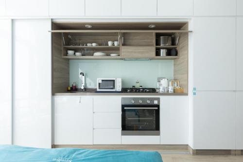 a kitchen with white cabinets and a microwave at Revelton Apartment Studio One in Dubai