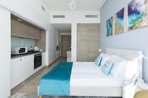 a bedroom with a white bed and a kitchen at Revelton Apartment Studio One in Dubai