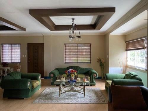 a living room with two green couches and a table at TGT GUEST HOUSE in Tagaytay