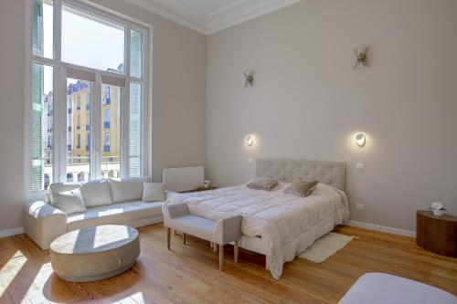 - une chambre blanche avec un grand lit et un canapé dans l'établissement Maison Bianchi - Clemenceau, à Nice