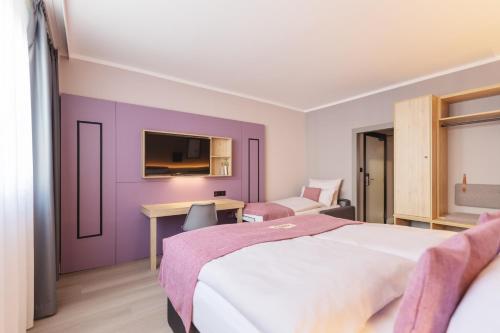 Schlafzimmer mit lila Wänden, einem Bett und einem Schreibtisch in der Unterkunft Yggotel Spurv in Berlin