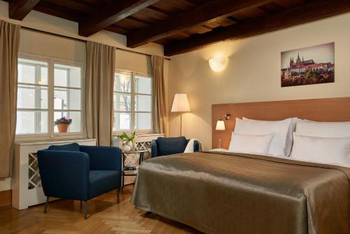 プラハにあるMostecká 12 Residenceのベッド1台と椅子2脚が備わるホテルルームです。