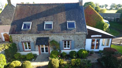 une ancienne maison en briques avec des fenêtres et des buissons bleus dans l'établissement Le cottage normand, à Saint-James