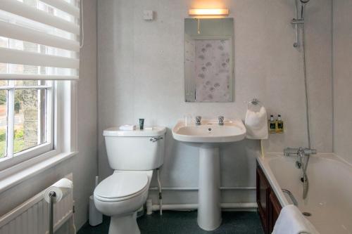 a bathroom with a toilet and a sink and a tub at Best Western Annesley House Hotel in Norwich