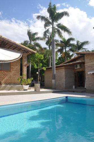 a swimming pool in front of a house with a palm tree at Hotel - Apart-hotel Chalé Executivo in Mossoró