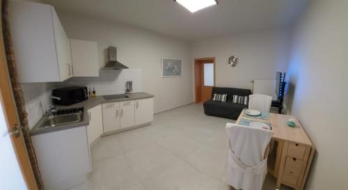 uma cozinha com armários brancos e uma mesa num quarto em Le Pepin Dort em Pepinster