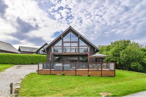 a house with a large deck on a lawn at 3 bed Lodge with EV point in Truro