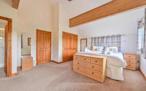 a bedroom with a large bed with a wooden dresser at 3 bed Lodge with EV point in Truro