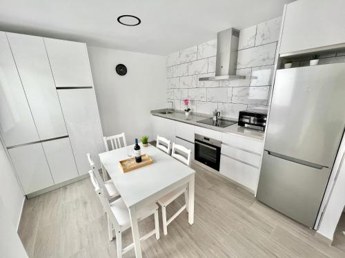 eine Küche mit einem weißen Tisch und Stühlen sowie einem Kühlschrank in der Unterkunft PISO EN EL CENTRO DE VELEZ MALAGA in Vélez-Málaga