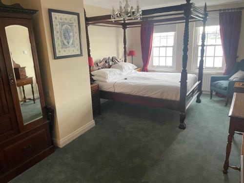 a bedroom with a canopy bed and a chair at The Portaferry Hotel in Portaferry