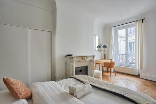 - une chambre blanche avec une cheminée et un lit dans l'établissement Résidence Beaubourg Le Marais by Studio prestige, à Paris