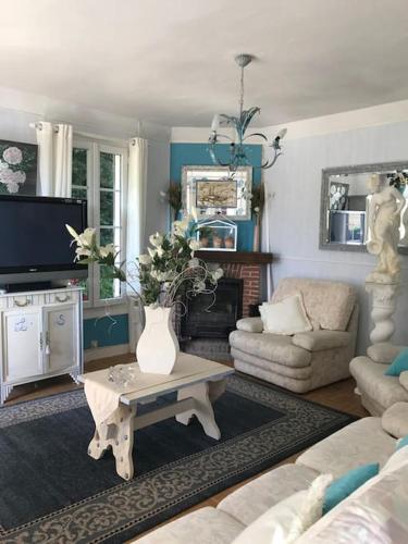 - un salon avec un vase de fleurs sur une table basse dans l'établissement Maison de gardien , manoir de Pichemont, » la maison des écureuils », à Harcanville
