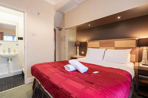 a bedroom with a large bed with a red blanket at Barrington Lodge in Crawley