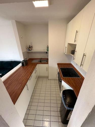 małą kuchnię z białymi szafkami i podłogą wyłożoną kafelkami w obiekcie Zentrales Appartement Ottobrunn w mieście Ottobrunn
