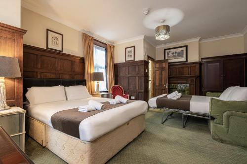 a hotel room with two beds and a chair at Barrington Lodge in Crawley