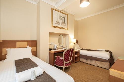 a hotel room with two beds and a desk at Barrington Lodge in Crawley