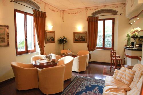 - un salon avec des chaises, des tables et des fenêtres dans l'établissement Hotel Tirreno, à Castiglioncello