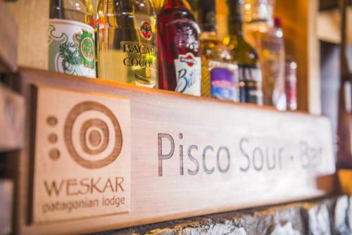 a sign for a pizza store with bottles of wine at Weskar Lodge Hotel in Puerto Natales