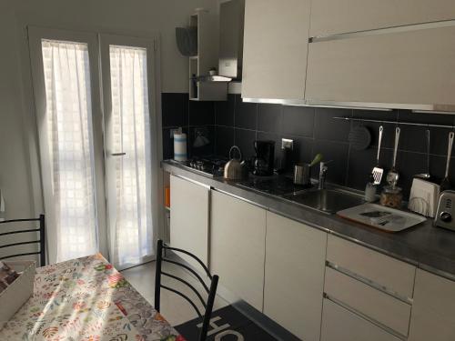 una cucina con armadi bianchi, tavolo, tavolo e tavolo e tavolo di Appartamento Firenze Centro Amorino con terrazzo a Firenze