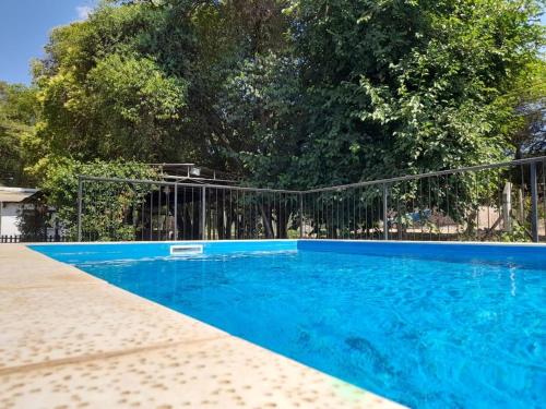 a blue swimming pool with a black fence at Cabañas Las Delicias in Salta