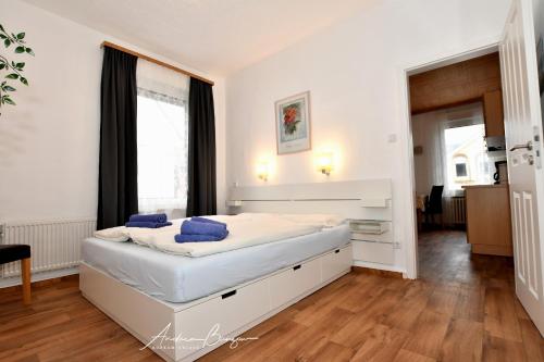 a bedroom with a white bed with blue pillows on it at Haus-Herrmann-1 in Borkum