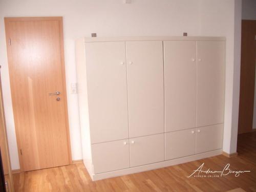 duża biała szafka w pokoju z drzwiami w obiekcie Gaestehaus-Flandern-2 w mieście Borkum