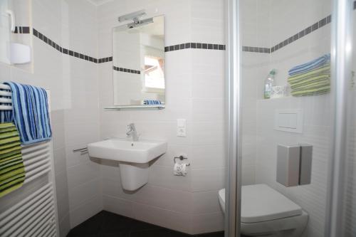 ein weißes Bad mit einem Waschbecken und einer Dusche in der Unterkunft "Gästehaus Flandern" 2 in Borkum