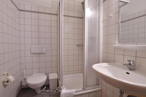 a bathroom with a toilet and a sink and a shower at Gaestehaus-St-Josef-2 in Borkum