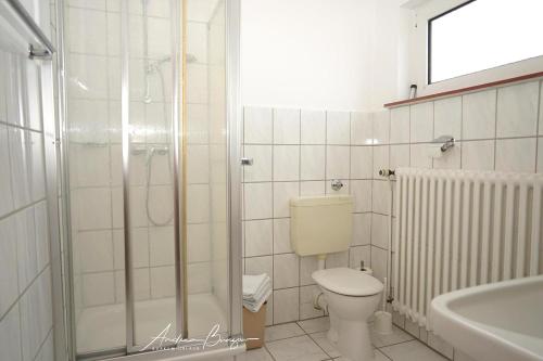 ein Bad mit einer Dusche, einem WC und einem Waschbecken in der Unterkunft Haus Königsdüne I/3 in Borkum