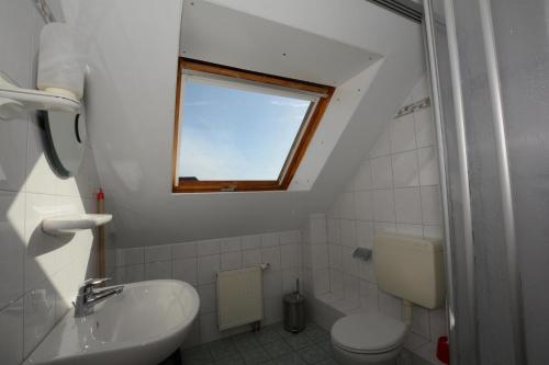 ボルクムにあるHaus-Koenigsduene-II-9のバスルーム(トイレ、洗面台付)、窓が備わります。
