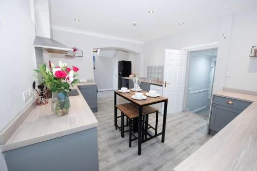 a kitchen with a table and a vase of flowers at Garden by the Bay Southport in Southport