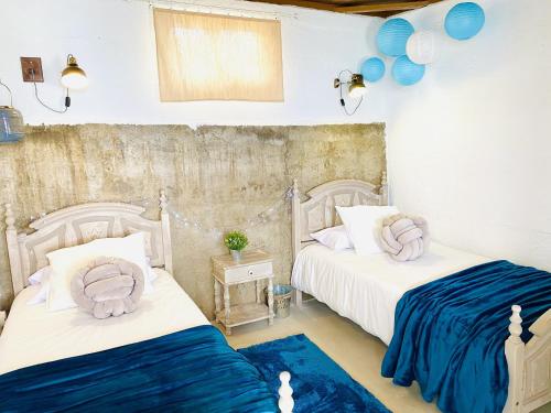 two beds in a room with blue and white at Alisios HOT TUB sauna piscina y naturaleza in Buzanada