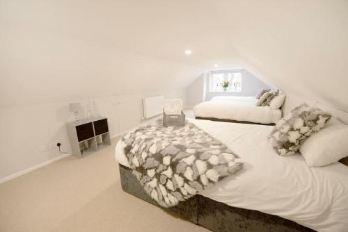 a white bedroom with a large bed and a window at Garden by the Bay Southport in Southport