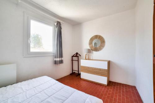 een slaapkamer met een bed, een spiegel en een raam bij Maison agreable pour 5 personnes a La Gueriniere in La Guérinière