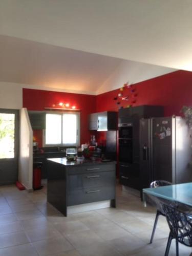Il comprend une cuisine dotée de murs rouges et d'un réfrigérateur noir. dans l'établissement jolie maison piscine privée, à Porto-Vecchio